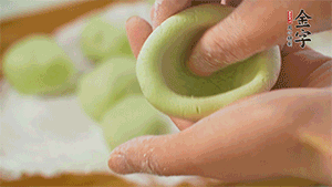 將均分的艾草面團搓成圓，挖一個窩，放入餡心，再搓成圓。