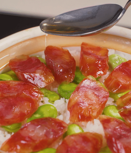 大米出現(xiàn)小孔時開蓋放香腸，往鍋邊淋入少許油，再燜煮8~10分鐘左右。