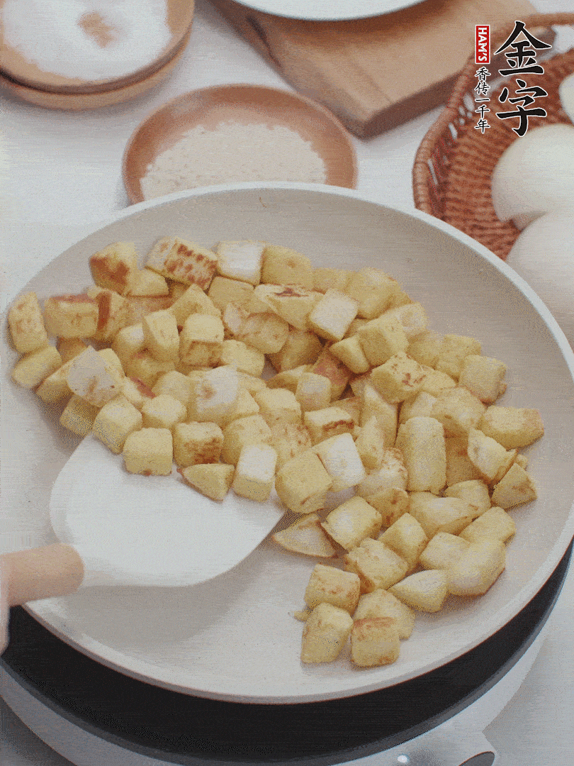 起鍋熱油，倒入饅頭丁，小火煎至蛋液凝固定型再翻面，饅頭丁部煎至金黃時(shí)盛起待用。