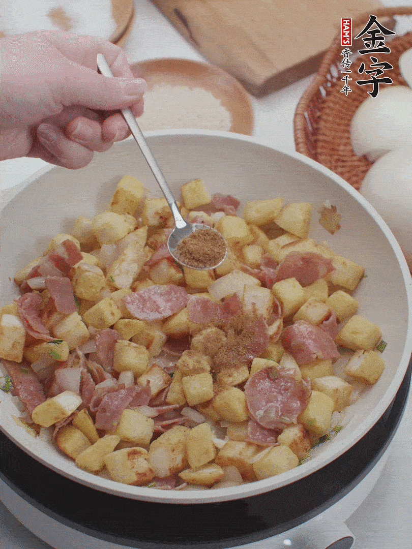 起鍋少油，煸香洋蔥丁、蔥白，加入金字培根火腿翻炒幾下，再加入饅頭丁、1小勺孜然粉、少許鹽翻炒均勻并鋪平。
