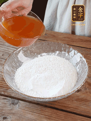 轉(zhuǎn)化糖漿、枧水、花生油攪拌均勻，加入面粉混合，醒發(fā)2小時(shí)。捏成23g一個(gè)的小球